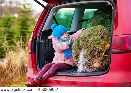 Adorable Little Preschool Girl With Christmas Tree Inside Of Family Car. Happy Healthy Child In Wint