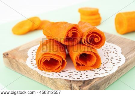 Homemade Carrot Pastille On Wooden Board, Closeup. Orange Rollup Of Pastila. Dehydrated Vegetable An
