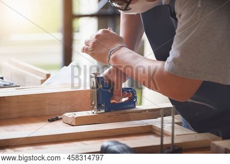 Entrepreneur Woodwork Holding A Tacker To Assemble The Wood Pieces As The Customer Ordered