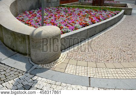 Crazy Annual Bed With A Pink-orange Combination Of Flowers. Large Retaining Walls Of Rounded Sandsto