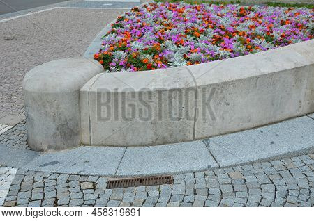 Crazy Annual Bed With A Pink-orange Combination Of Flowers. Large Retaining Walls Of Rounded Sandsto