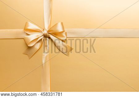 Top View Of Gold Ribbon Rolled And Yellowbow Isolated On Colored Background. Flat Lay With Copy Spac