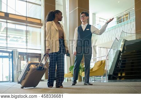 Young Smiling Manager Of Modern Hotel Consulting Female Traveler In Lounge