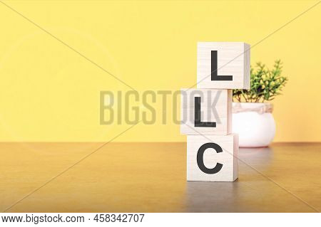 Three Wooden Cubes With Letters - Llc, On Yellow Background, Llc - Limited Liability Company. Front 