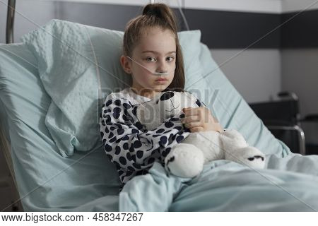 Under Treatment Ill Little Girl Resting In Pediatric Healthcare Facility While Holding Teddybear. Si