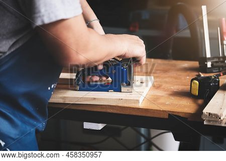 Entrepreneur Woodwork Holding A Tacker To Assemble The Wood Pieces As The Customer Ordered
