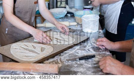 A Baker Shapes And Cuts Traditional French Fougasse Bread. Front View.