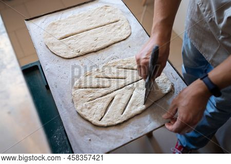 A Baker Shapes And Cuts Traditional French Fougasse Bread. Front View.
