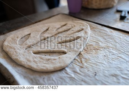 A Baker Shapes And Cuts Traditional French Fougasse Bread. Front View.