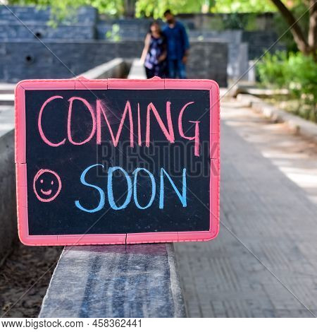 Indian Couple Posing For Maternity Baby Shoot. The Couple Is Posing In A Lawn With Green Grass And T