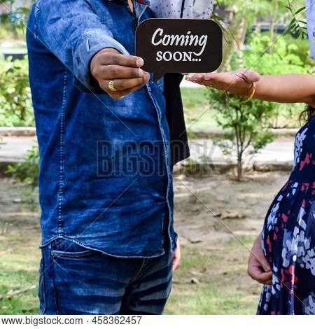 Indian Couple Posing For Maternity Baby Shoot. The Couple Is Posing In A Lawn With Green Grass And T