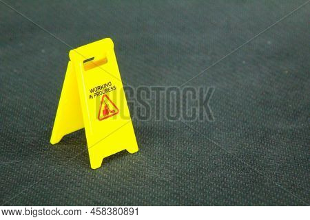 A Yellow Sign With The Words Work In Progress With A Blurred Background