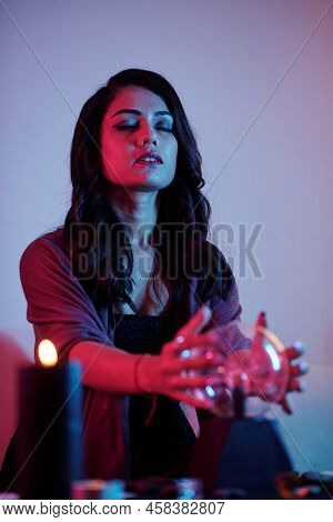 Concentrated Young Dark Witch Trying To Tell Fortunes With Crystal Ball