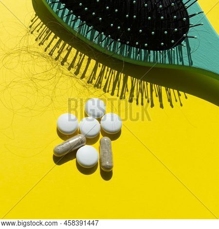 Pills And Fallen Hair On A Yellow Background. Baldness And Hair Loss Problem