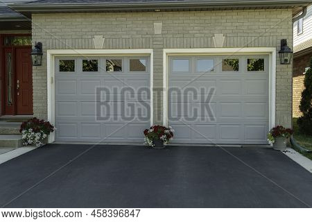 Two Separate Garages In One House With Asphalt At The Entrance In Front Of The Gate