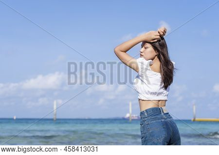 Lifestyle Image Of A Carefree Traveling Woman Posing On Sandy Beach Near Turquoise Colored Ocean In 
