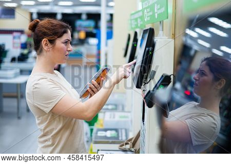 A Frustrated Woman Uses A Self-checkout Counter. The Girl Does Not Understand How To Independently B