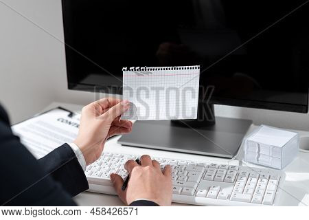 Businesswoman Holding Pen And Important Message Wtitten On Paper On Desk With Computer, Clipboard An