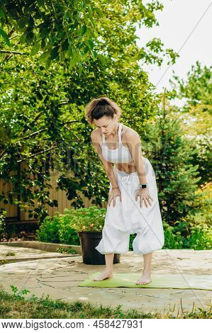 Young Woman Practices Yoga In The Summer Garden. Vacuum Exercise. Nauli Is One Of The Kriyas Or Shat