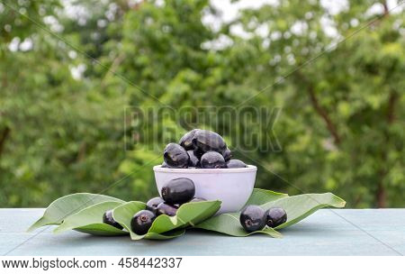 Jamun Or Syzygium Cumini In A Bowl With Leaves Isolated On Wooden Background With Copy Space, Also K