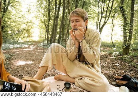 Barefoot Man Playing Jews Harp Near Wife In Forest