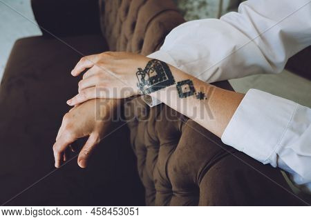 Female Hands With Tattoo On Sofa At Home. Relaxing Woman Tattoo Hand
