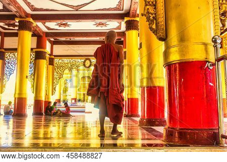 Bago, Myanmar - December 02 2012 : A Buddhist Monk With Robes Is Walking Inside At A Pagoda And Gold