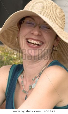 Risa de mujer que llevaba gafas y sombrero de paja