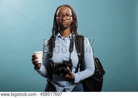 Serious Looking Professional Photographer Having Dslr Device And Cup Of Coffee While Looking At Came
