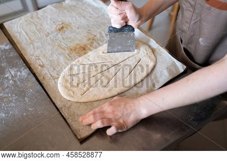A Baker Shapes And Cuts Traditional French Fougasse Bread. Front View.