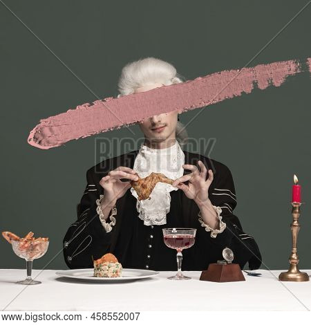 Creative Portrait Of Young Elegant Man In Peruke And Vintage Jacket Sitting At Table Isolated On Dar