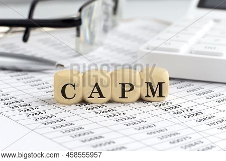 Wooden Cubes With The Word Capm On Financial Background With Chart, Calculator, Pen And Glasses, Bus