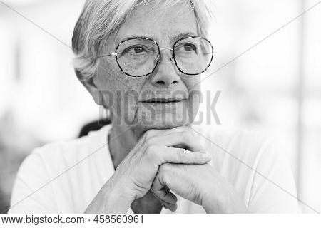 Black And White Portrait Of A Beautiful Senior Caucasian Woman With Eyeglasses As She Looks Thoughtf