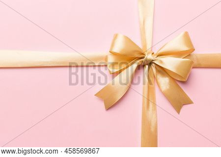 Top View Of Gold Ribbon Rolled And Yellowbow Isolated On Colored Background. Flat Lay With Copy Spac