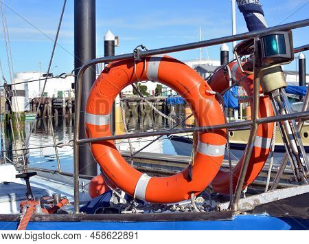 Safety At Sea - Closeup Detail Of Two Orange Life Buoys On The Deck Of A Yacht In A Marina.