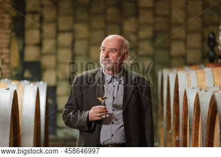 Senior Caucasian Tourist, Greybeard Elegant Man Tasting Red Wine In An Underground Wine Cellar Of Th