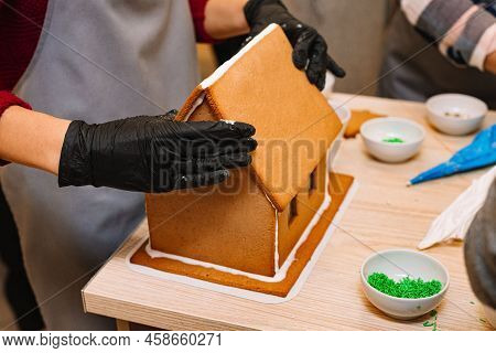 The Process Of Making A Gingerbread House, Gluing The Ginger Roof With Icing, Squeezing Tight