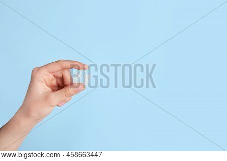 Woman Holding Anti-snoring Device On Light Blue Background, Closeup. Space For Text