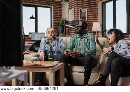 Multiethnic Group Of Friends Using Virtual Reality Glasses To Play Video Games On Television. Having