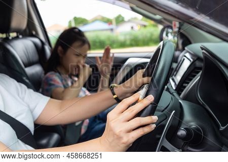 Asian Woman Smoking Cigarette While Driving Inside The Car And The Child Choking Of Smoke, Bad Smell