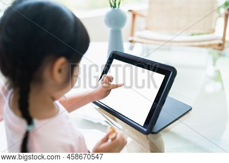 Asian Girl Looking And Touch On White Screen At The Tablet Screen Attentively. Overstimulated Childr