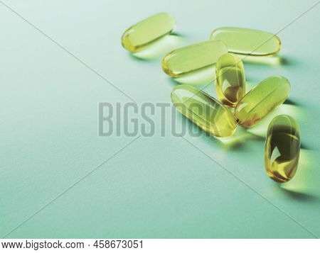 Yellow Softgels Lie On A Green Surface. Fish Oil.  Vitamins And A Healthy Lifestyle. Background Or B