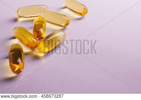 Yellow Softgels Lie On A Pink Surface. Fish Oil.  Vitamins And A Healthy Lifestyle. Background Or Ba