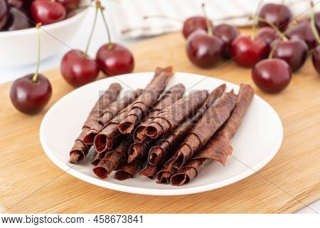Red Fruit Leather Rolls. Mashed Sweet Cherry Snack. Homemade Pastila On White Plate On Wooden Board.