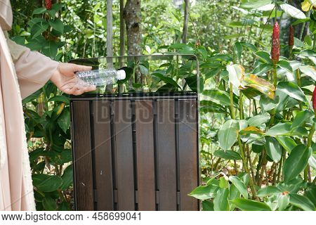 Women Hand Throwing An Empty Plastic Water Bottle In The Garbage Trash Or Bin
