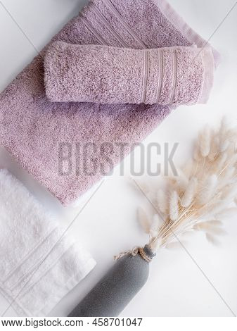 White And Pink Twisted Towels With Dried Flowers On The White Background.