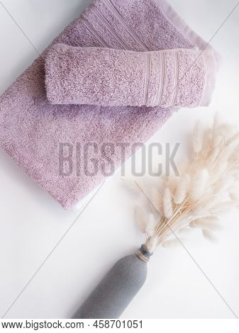 Pink Twisted Towels With Dried Flowers On The White Background.