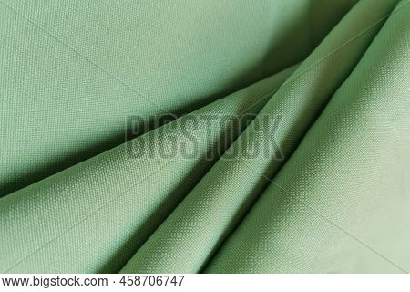 Green Crumpled Or Wavy Fabric Texture Background. Abstract Linen Cloth Soft Waves. Gabardine Wool Fa