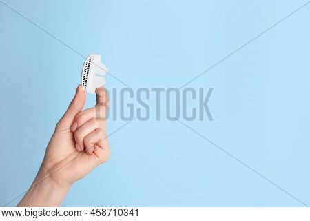 Woman Holding Anti-snoring Device On Light Blue Background, Closeup. Space For Text