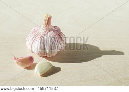 Head Of Fresh Garlic And Two Cloves Of Garlic On Light Wooden Background
